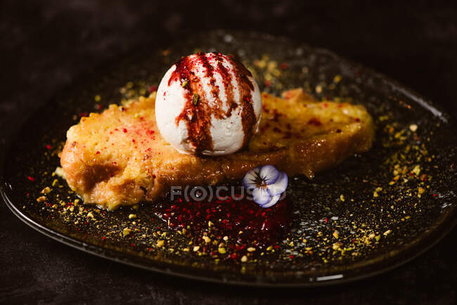 Yummy French toast with meringue milk ice cream scoop covered with sweet berry sauce on plate with condiments in restaurant on dark background — Stock Photo