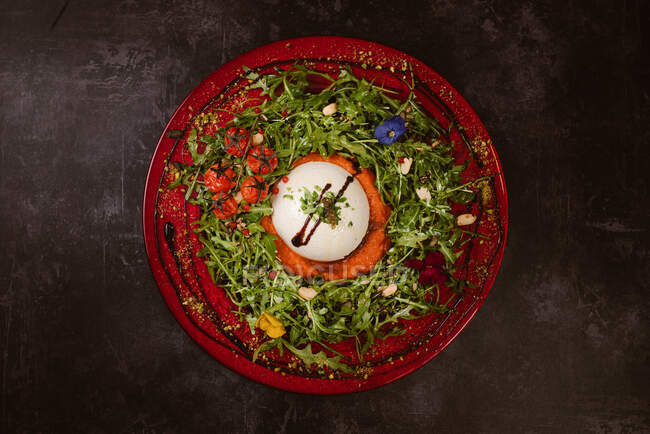Overhead view of yummy burrata cheese on cold tomato cream with arugula leaves and cherry tomatoes with truffles and peanuts — Stock Photo