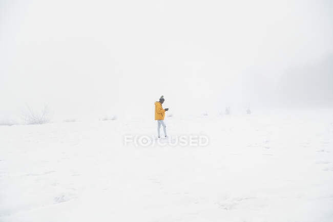 Side view full length of African American male in outerwear standing on snowy ground in winter day — Stock Photo