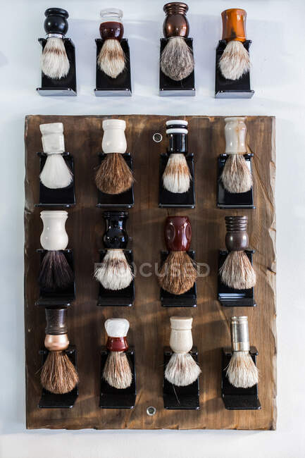 Collection of assorted brushes for shaving routine in barbershop hanging on wall for beauty treatments — Stock Photo