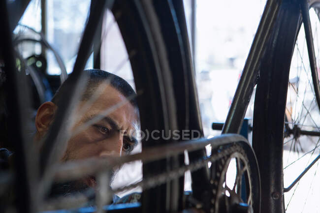 Meccanico maschio concentrato con barba nei guanti riparazione biciclette in officina moderna — Foto stock