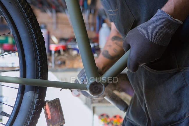 Обрізання чоловічої механіки в рукавичках ремонт велосипеда в сучасному майстерні — стокове фото