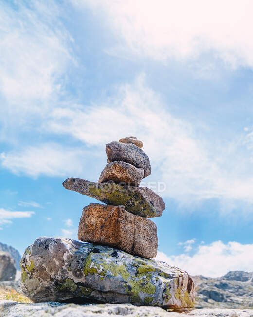 Heap of rough stones against river and mount under blue cloudy sky in sunlight — Fotografia de Stock
