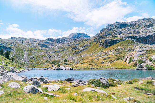 Herrliche Landschaft mit rauen felsigen Gebirgszügen rund um den ruhigen blauen See unter klarem blauen Himmel an einem sonnigen Sommertag in den katalanischen Pyrenäen — Stockfoto