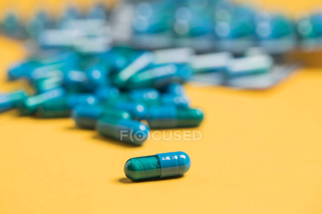 De dessus de capsules médicales bleues placées sur fond jaune — Photo de stock