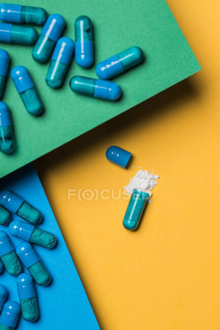 Hoher Inhaltswinkel des Medikaments aus blauer Kapsel auf gelbem Hintergrund gegossen — Stockfoto