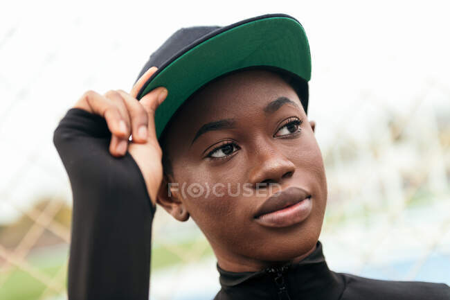 Niedriger Winkel einer jungen Afroamerikanerin in Freizeitkleidung, die bei Tageslicht mit erhobenem Finger in die Kamera blickt — Stockfoto