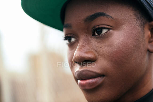 Jeune femme afro-américaine en tenue décontractée regardant la caméra avec le doigt vers le haut en plein jour — Photo de stock