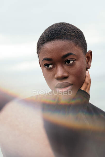 Young contemplative ethnic female with short hair touching face in daylight — Stock Photo