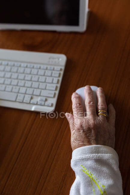 Crop anonymous patient with keyboard against tablet with doctor on screen during video call in house — Stock Photo