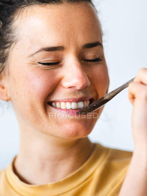 Junge blonde, fröhliche Frau in lässiger Kleidung isst gesunde Nahrung aus natürlichen Kokosnussschalen im hellen Raum — Stockfoto