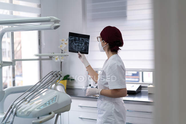 Vista laterale del medico malinconico in uniforme esame radiografia foto del paziente mentre si pensa alla diagnosi — Foto stock