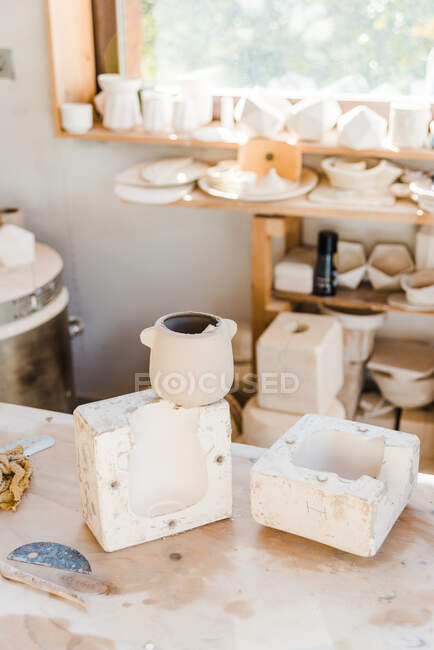 Light studio with ceramic pots on surface near shelf with handmade clayware — Fotografia de Stock