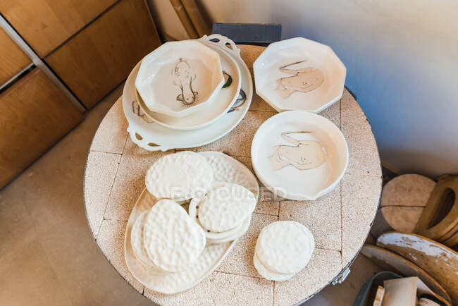From above of assorted dishware made of clay placed on round table in pottery workshop — Fotografia de Stock