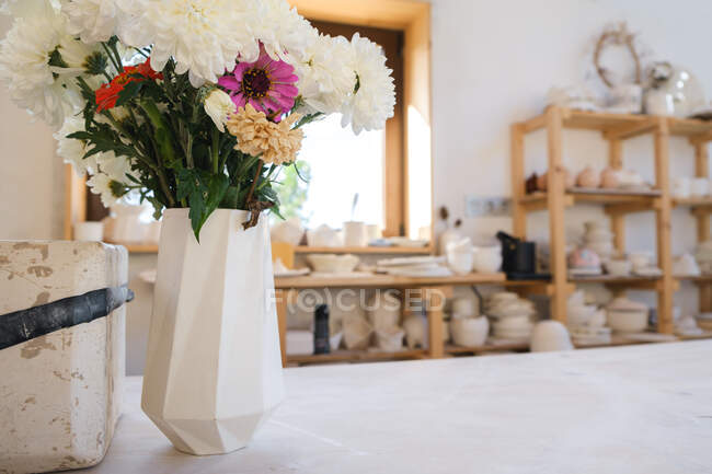 Vase en céramique fait à la main en atelier de poterie avec des fleurs en fleurs — Photo de stock
