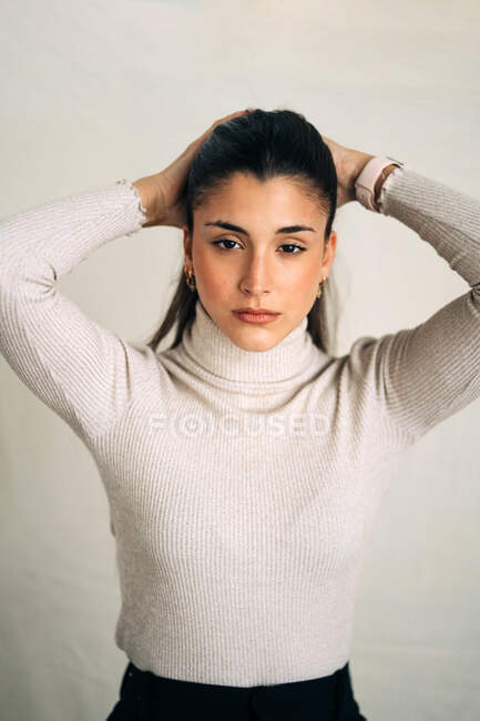 Unemotional young thoughtful female looking at camera in studio background in daytime — Stock Photo