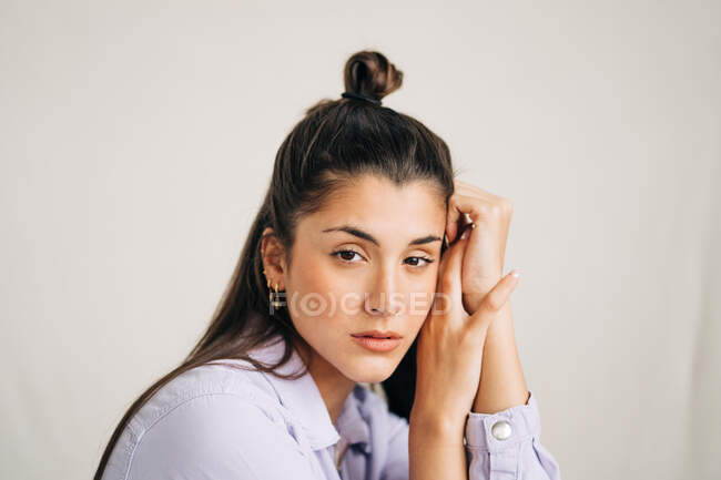 Unemotional young thoughtful female looking at camera on studio background in daytime — Stock Photo