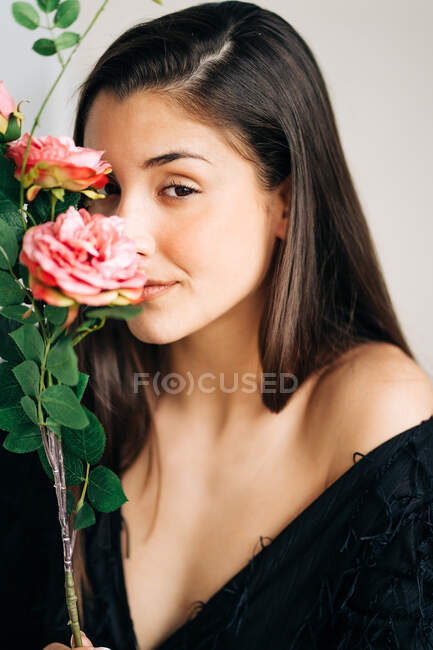 Молода чуттєва жінка в чорному одязі з квітучою квіткою дивиться на камеру — стокове фото