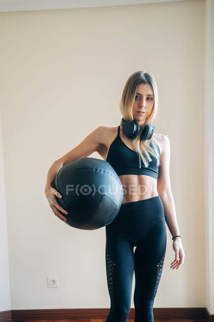 Donna che indossa abbigliamento sportivo e caschi mentre tiene una palla con le mani — Foto stock