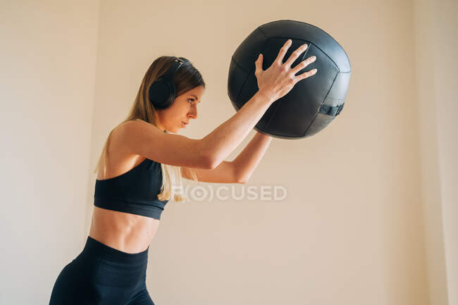Mujer con ropa deportiva y cascos mientras sostiene una pelota con las manos - foto de stock