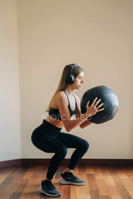 Femme portant des vêtements de sport et des casques tout en tenant une balle avec ses mains — Photo de stock