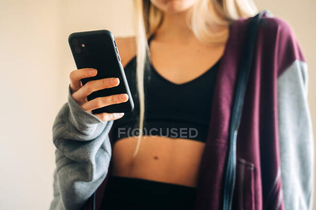 Fit female in headphones listening to music and surfing cellphone after workout at home — Stock Photo