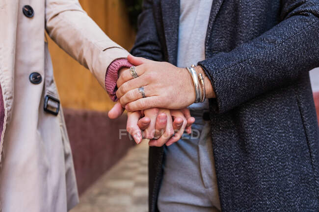 Ernte unkenntlich verliebtes Paar in stylischen Mänteln, die auf der Straße stehen und sich sanft an den Händen halten — Stockfoto