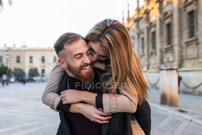 Verspielter Mann huckepack fröhliche Frau beim Spaß in der Stadt Straße — Stockfoto