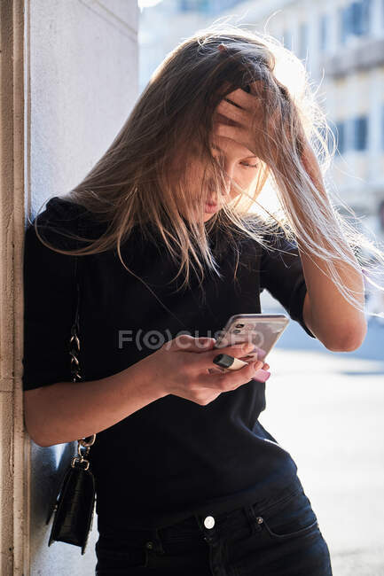 Recadrage de belle jeune fille blonde en utilisant son smartphone regardant inquiet — Photo de stock