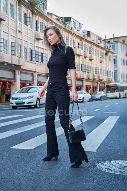 Belle jeune fille blonde se promenant dans le centre-ville chinois et traversant la rue au passage supérieur — Photo de stock