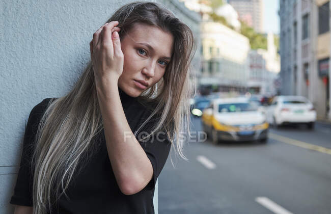 Beautiful blond young girl posing around Chinese downtown with black clothes — Stock Photo