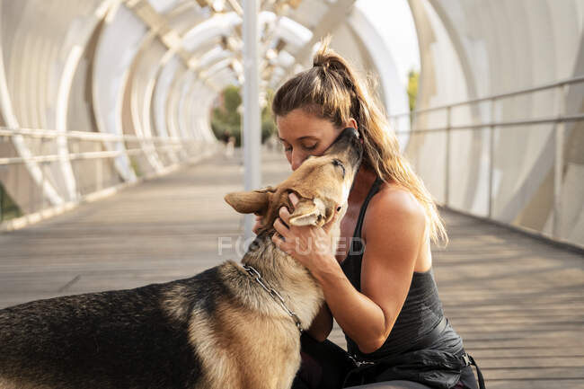 Frau in Sportbekleidung umarmt Schäferhund an der Leine beim Lauftraining am Tag — Stockfoto