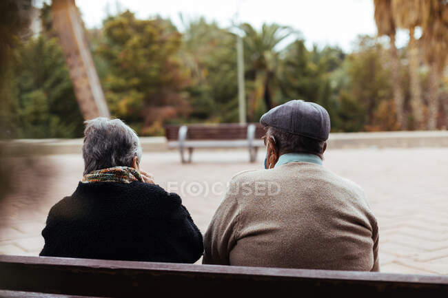 Rückansicht eines nicht wiederzuerkennenden älteren Ehepaares, das auf einer Parkbank sitzt — Stockfoto