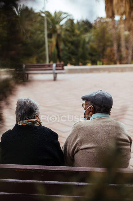 Вид ззаду на невпізнавану літню пару, що сидить на лавці парку — стокове фото