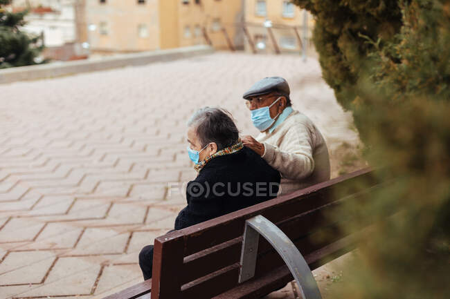 Vista trasera de una pareja de ancianos irreconocibles sentados en un banco del parque - foto de stock