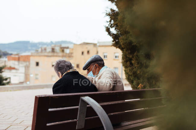 Vue arrière d'un couple âgé méconnaissable assis sur un banc de parc — Photo de stock