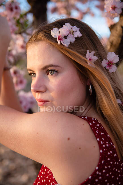 Mulher loira com cabelos longos posando sob uma amendoeira florida — Fotografia de Stock