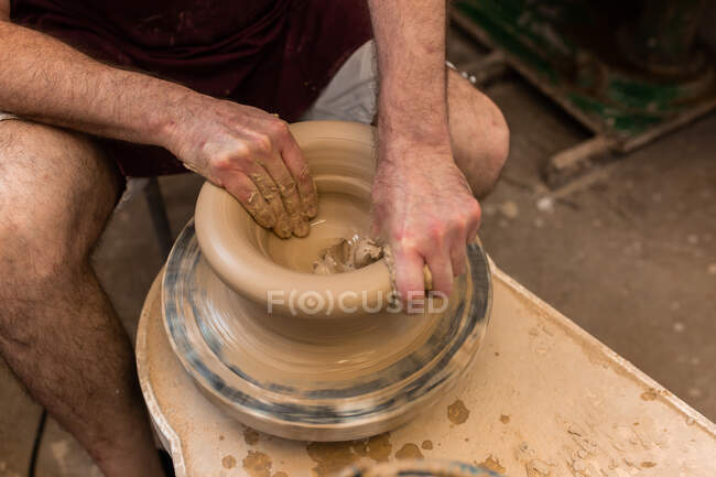 Растениеводство неузнаваемый скульптор с оборудованием придавая форму во время скульптуры с коричневой глиной на бросать колесо — стоковое фото