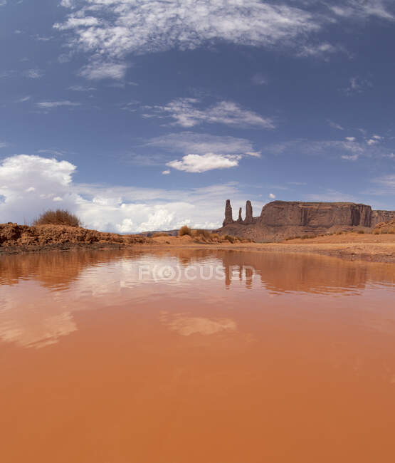 Eau calme rouge située contre le ciel nuageux et les formations rocheuses du parc national avec zone désertique aux États-Unis dans la nature — Photo de stock