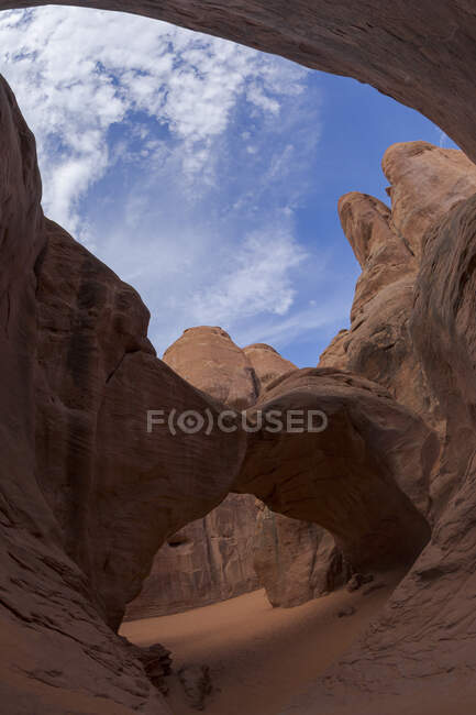 Pittoresca veduta della formazione rocciosa ad arco situata tra ruvide scogliere in un'area arida del parco nazionale negli Stati Uniti contro il cielo nuvoloso — Foto stock