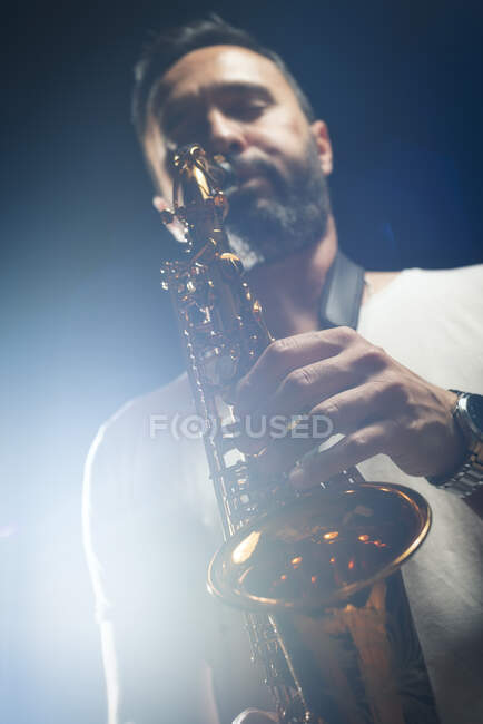 Чоловічий музикант в стильному вбранні грає альт-саксофон під час джазового концерту — стокове фото