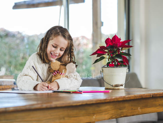 Corte pequena menina desenho com lápis multicoloridos na folha de papel na sala de luz — Fotografia de Stock