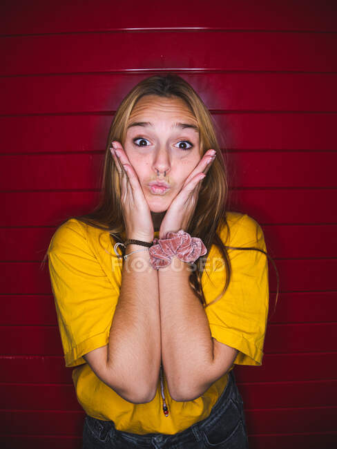 Молода жінка робить жест похмурості, стоячи на червоному смугастому фоні — стокове фото