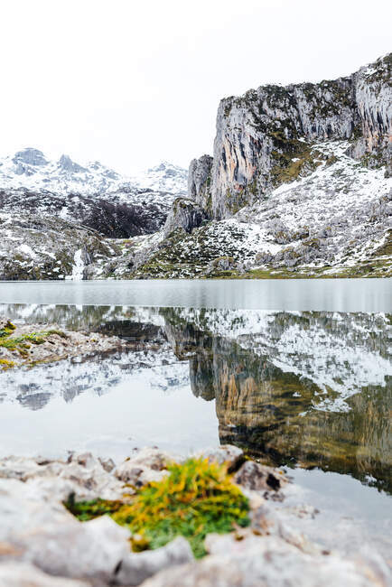 Increíble paisaje de cordillera severa áspera con pendientes en la nieve y el frío lago congelado en el fondo en el día claro de invierno - foto de stock