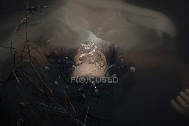 Desde arriba vista trasera de la cosecha anónima turista femenina nadando con tela ondulada en el lago en el crepúsculo - foto de stock