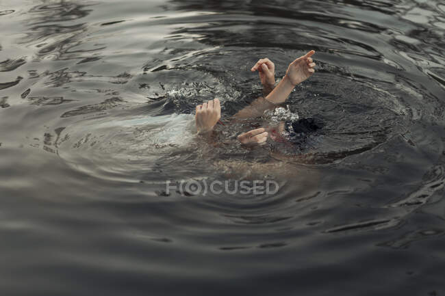 From above of crop anonymous travelers with raised arms swimming in pure water during trip — Stock Photo