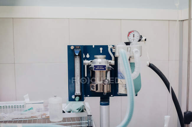 Машина для анестезии с ребристыми пластиковыми шлангами рядом с металлической канистрой и манометром давления в ветеринарной клинике — стоковое фото