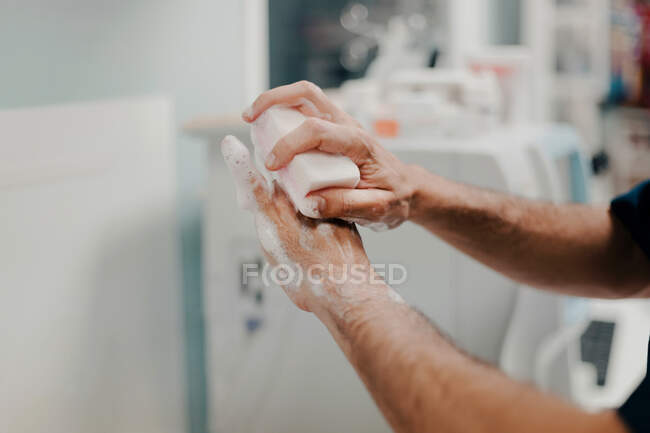 Vista lateral da colheita de médico masculino irreconhecível desinfectando as mãos no hospital — Fotografia de Stock