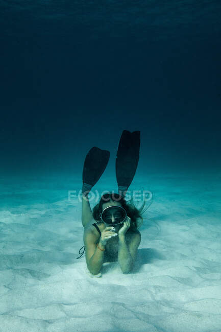Slim female in swimsuit and flippers swimming underwater in turquoise sea — Stock Photo
