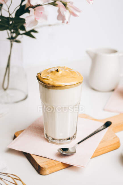 Cucchiaino con dolce schiuma montata sopra latte fresco gustoso servito su tagliere in legno in cucina moderna leggera — Foto stock